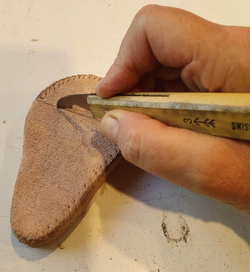 Hand with knife cutting leather