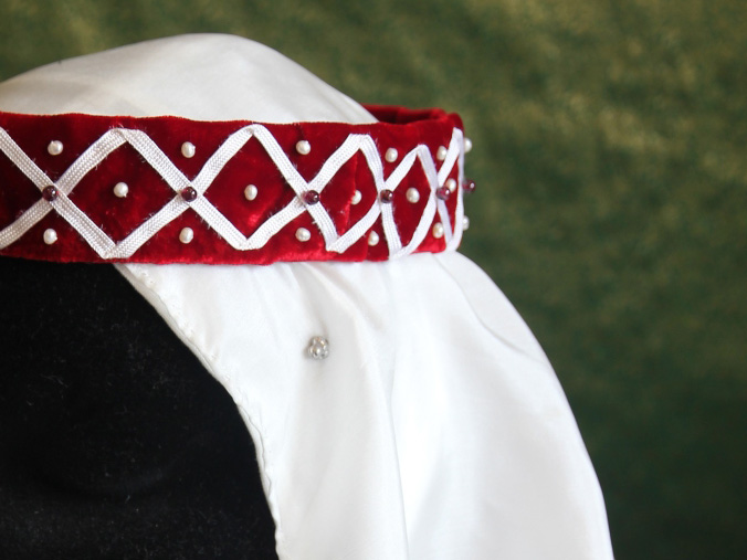 Headdress comprising a red velvet fillet with white ribbon decoration, and a white silk veil