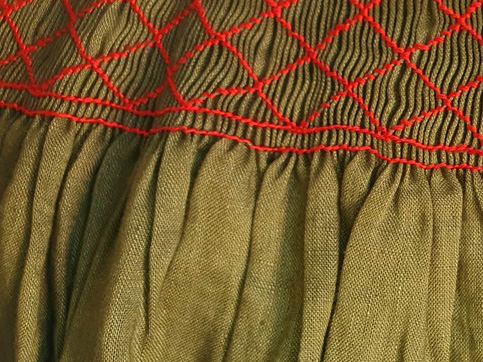 Top of an apron in green linen, with decorative smocking along the top in red silk