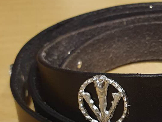 Part of a leather belt with a pewter decoration of an arrowhead inside a circle