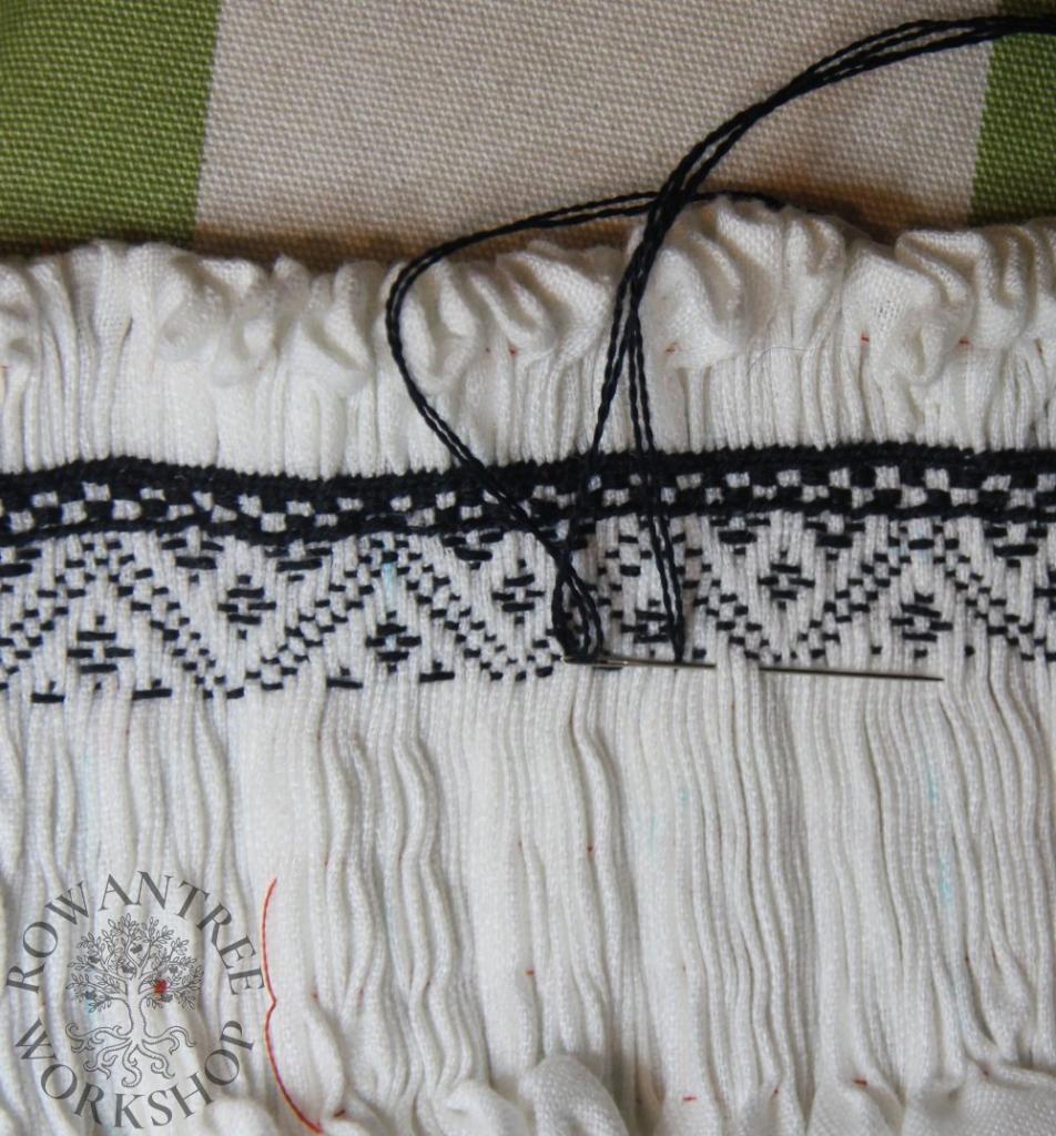 Cose up of embroidery with several rows worked over pleats