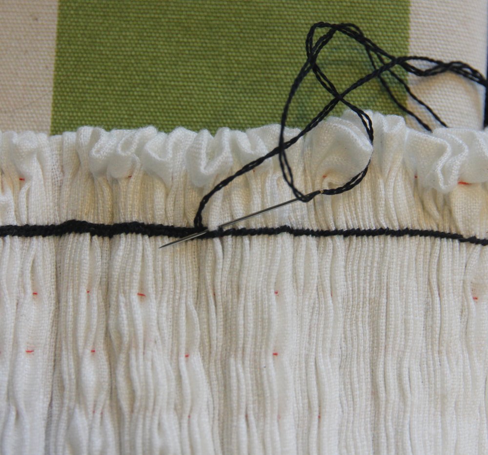 Cluse up of needle sewing a tight row of stitches over pleats