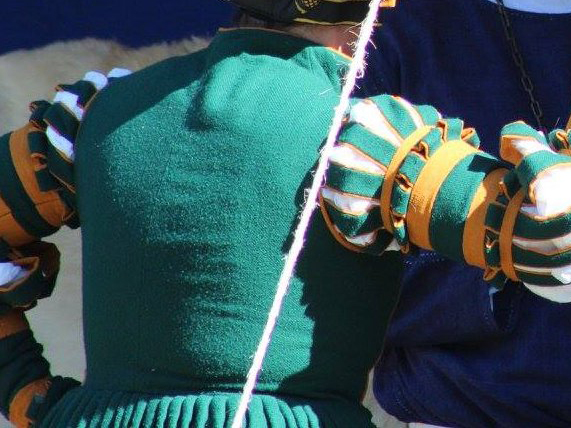 Back view of woman's torso wearing a German gown in heavy green wool with a high neck, slashed sleeves and gold bands