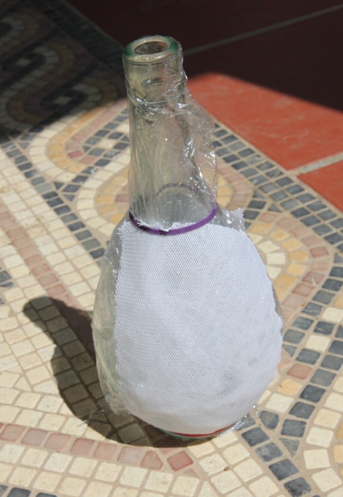 Glass bottle with canvas shaped around it, drying in the sun