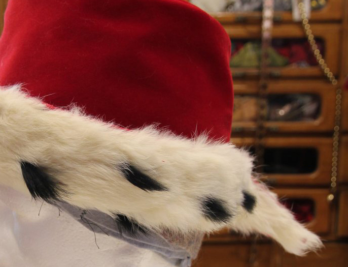 Part of a red hat, with a fur covered brim ending in a tail out the back