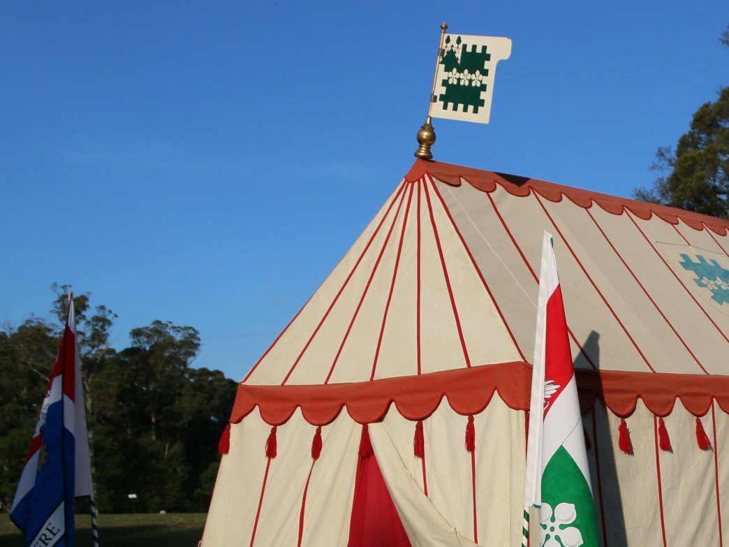 Front of a rectangular tent with a peaked roof and red striped decoration