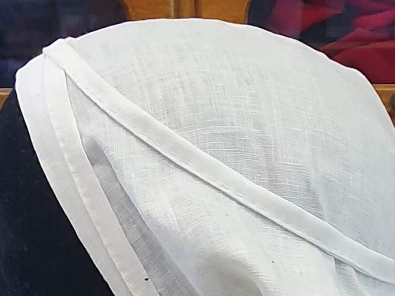 Part of a women's white cap, tied over the top of the head