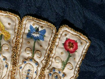 A glove cuff in satin, with tabs embroidered with flowers in silk and gold
