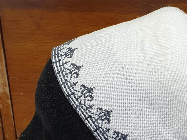 White linen cap with the edge decorated with black embroidery