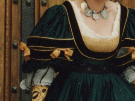Torso of a woman wearing a green silk German gown, with very large sleeves, decorated with bows
