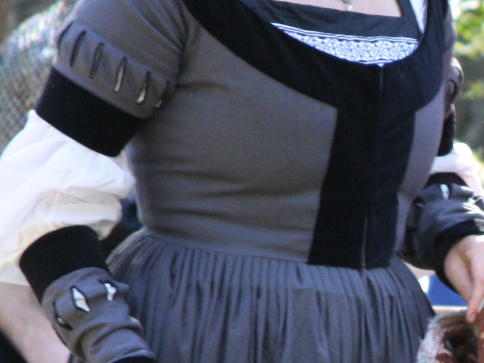 Woman's torso wearing German gown in grey linen, decorated with contrast bands and small slashes in the upper sleeves