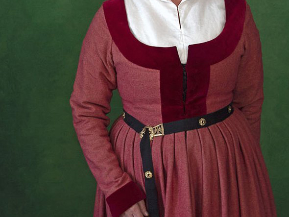 Woman's torso wearing a pink wool German gown, with red velvet edges