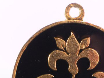 Top of a medallion in black with a gold lily
