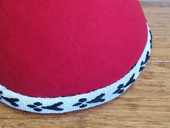 Round red cap, with a tablet-woven trim