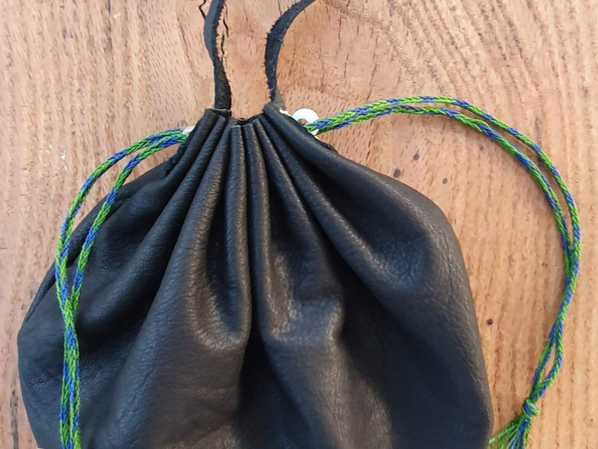 Top section of black leather purse with two silk drawstrings