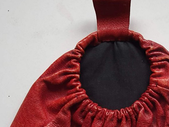Top section of a red leather purse gathered around a ring frame