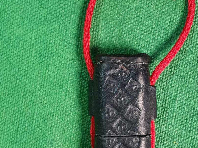 Part of a small leather needle-case with attached cord