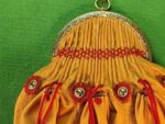 Top of pleated leather purse with embroidery over the pleats and three small pouchlets closed with cords